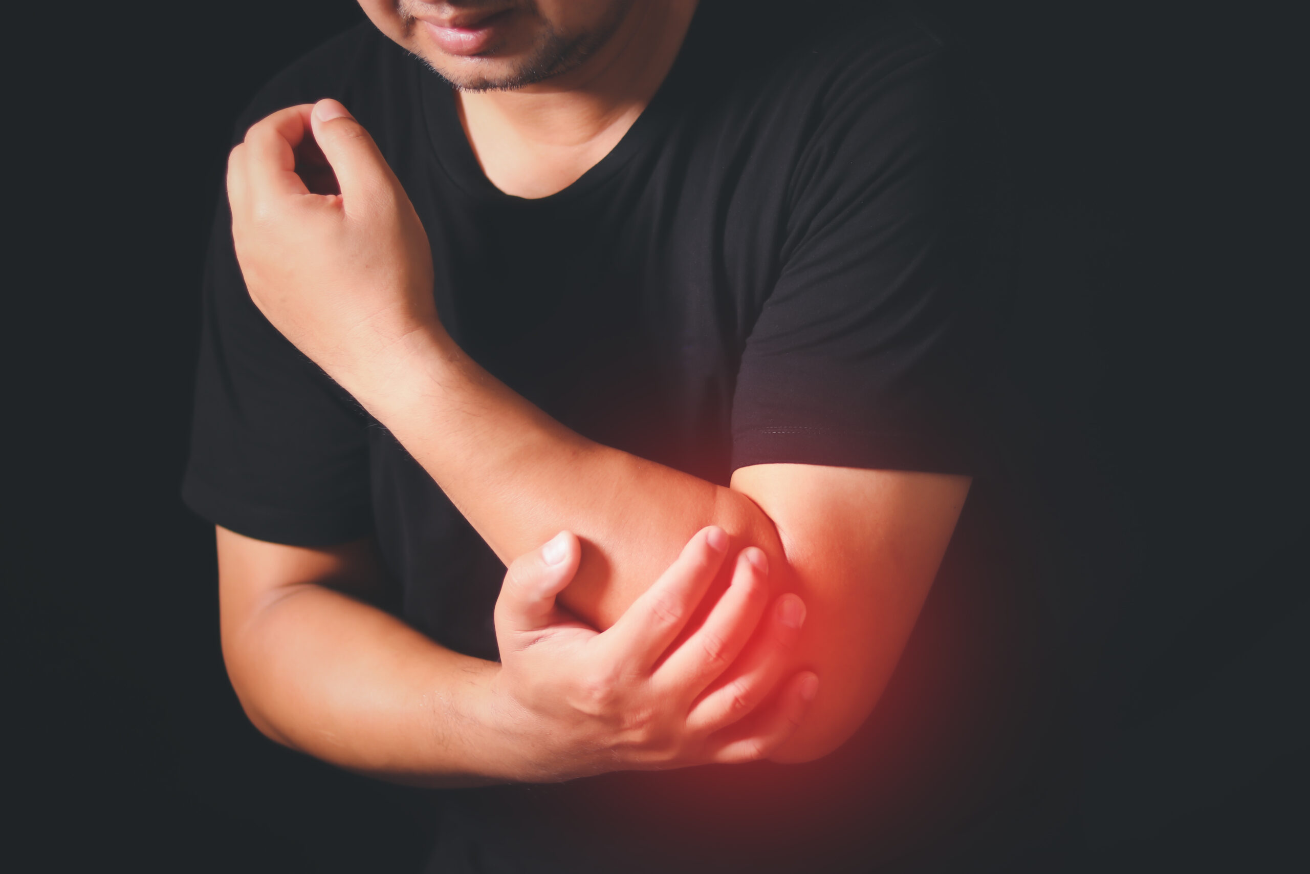 Man Pain in the elbow. The hearth is highlighted in red. Close up Man feeling a pain in his elbow on black background, Carpal tunnel syndrome, arthritis, neurological disease concept.